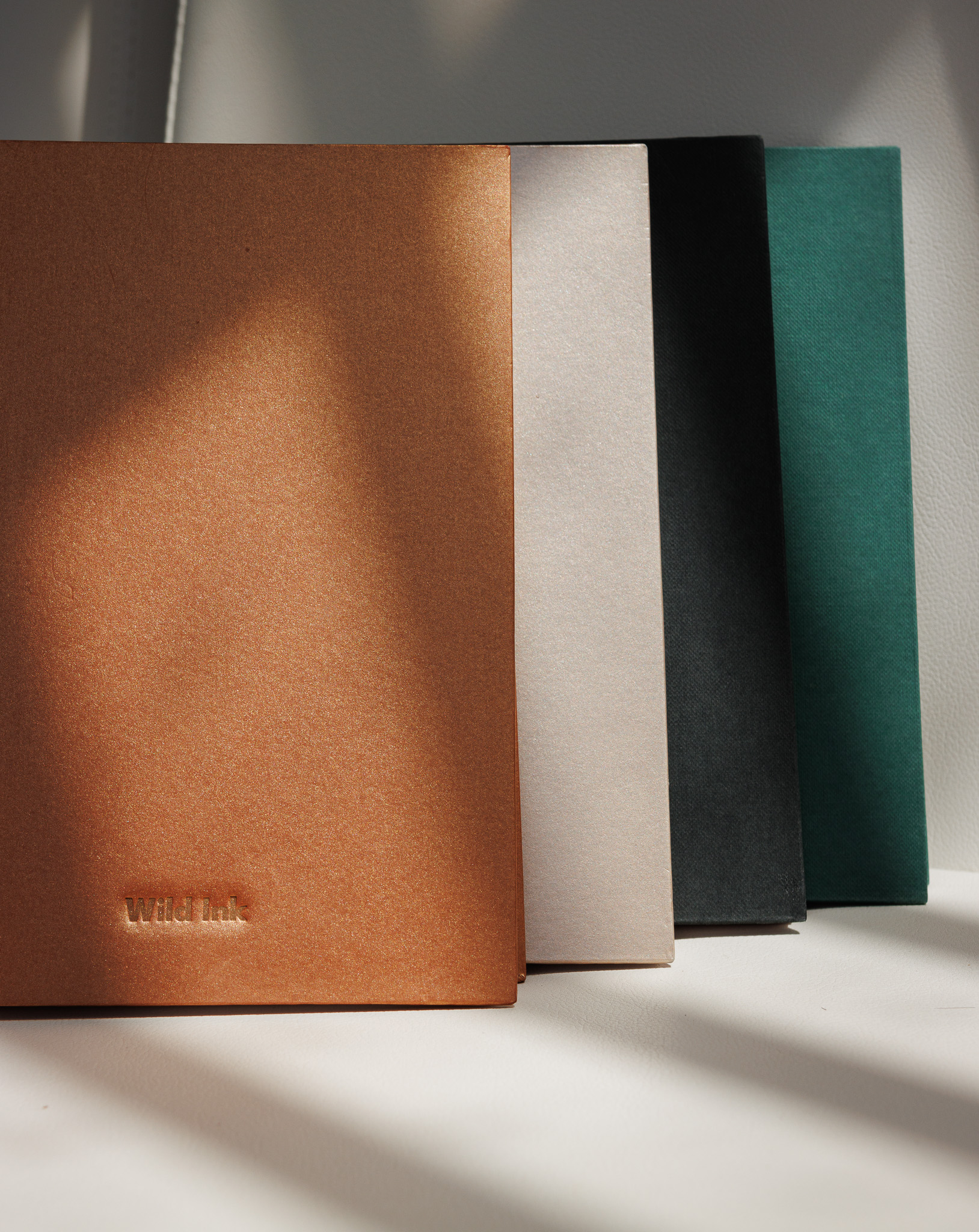 Sketchbooks Wild Ink en naranja, arena, negro y verde, vistos de canto