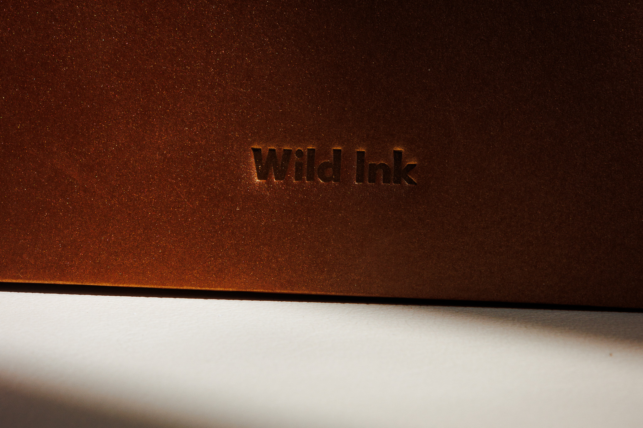 Detalle en primer plano del sello Wild Ink grabado en la portada, con luz cálida